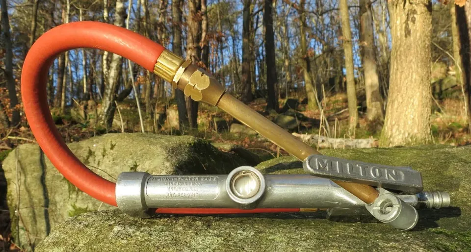 A red air chuck tire gauge with an orange hose on a rock