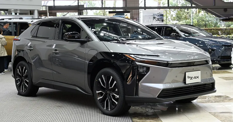 A grey Toyota bZ electric SUV on display in a showroom, seen from the front left