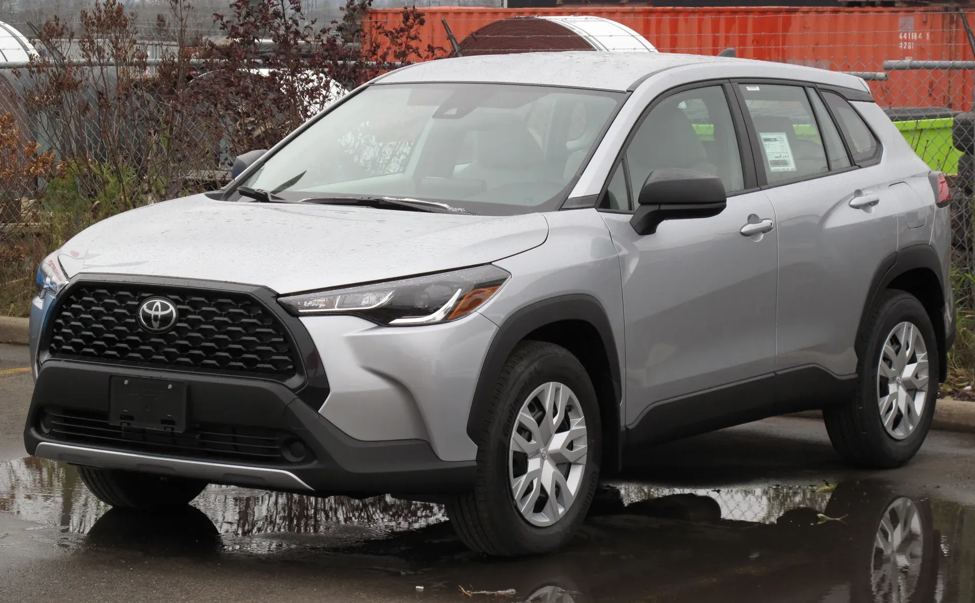 A silver Toyota Corolla Cross L compact SUV parked on a wet lot