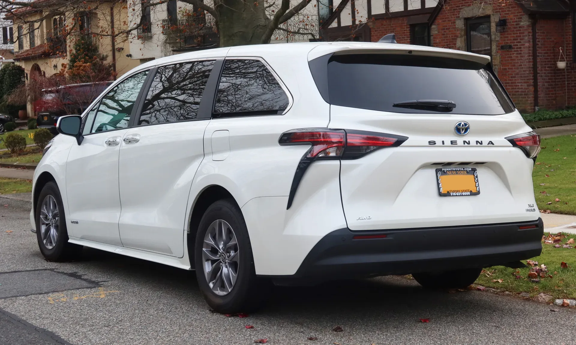 The rear of a white 2021 Toyota Sienna XLE Hybrid minivan with Sienna and AWD badges on the tailgate