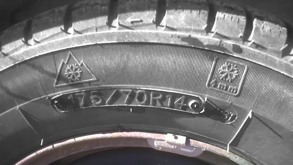 Gros plan sur le flanc d'un pneu avec le pictogramme de la montagne à trois sommets et du flocon à côté de la dimension